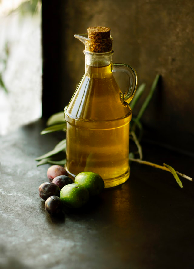 Bottiglia di olio di oliva su un tavolo e con olive